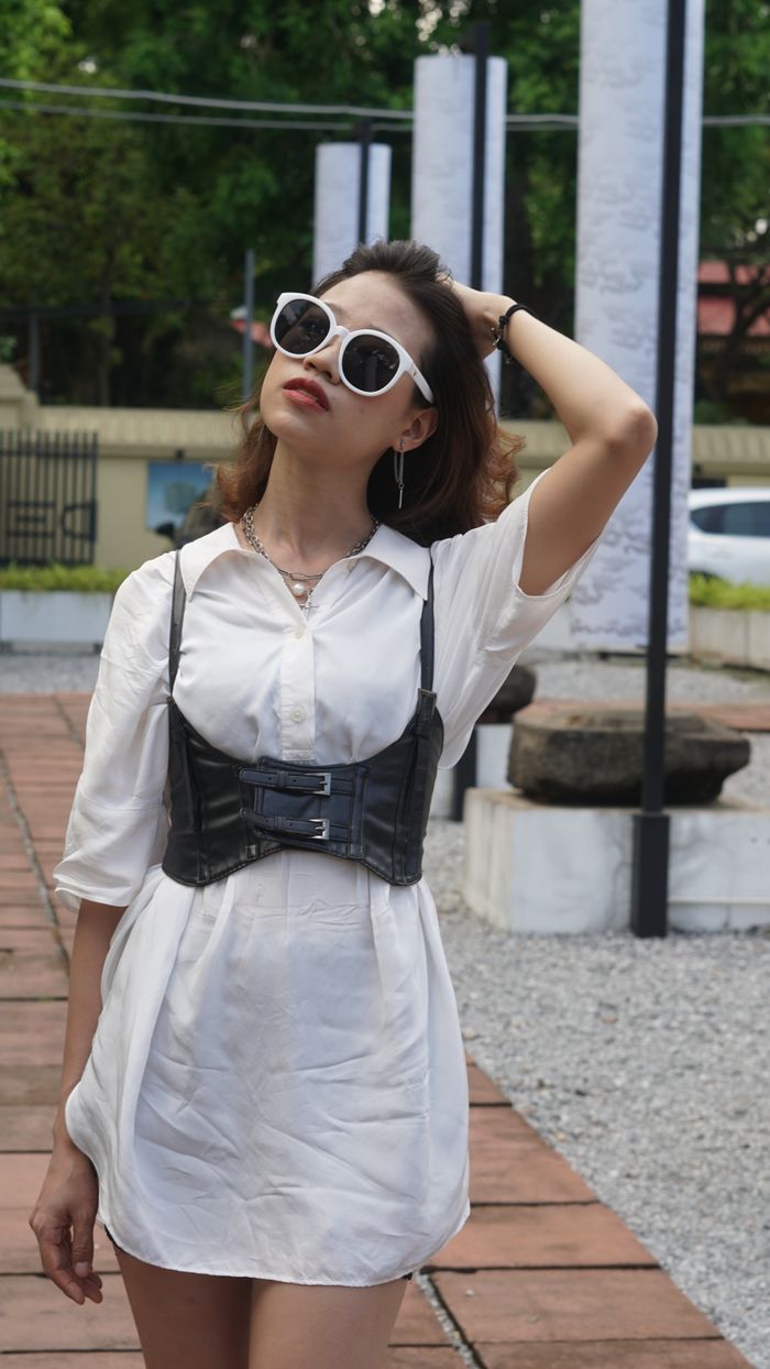 Portrait of a fashionable woman in sunglasses adjusting hair in an urban outdoor area.
