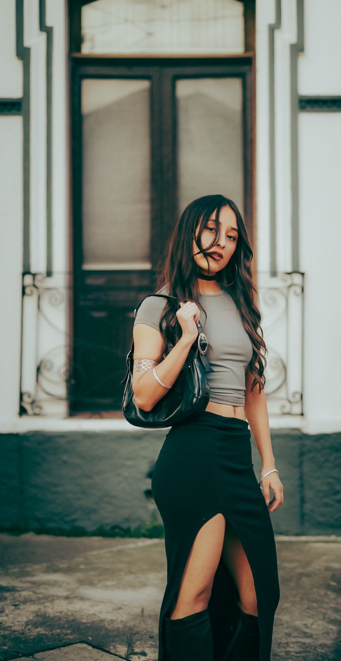 Stylish woman in urban setting wearing chic attire, posing confidently outdoors.